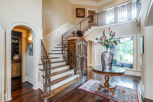 stairway with hardwood / wood-style flooring, crown molding, and a high ceiling