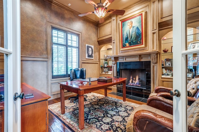 office space with a fireplace, wood-type flooring, built in features, and ornamental molding