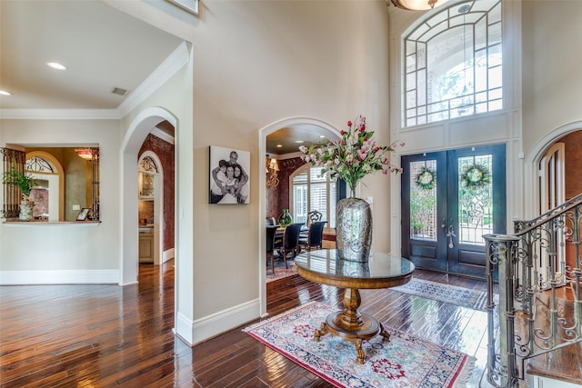 foyer with french doors, dark hardwood / wood-style flooring, a wealth of natural light, and crown molding