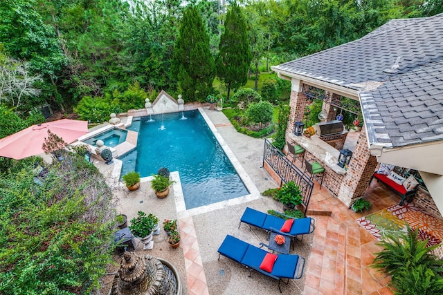 view of pool featuring an in ground hot tub, an outdoor kitchen, a bar, a patio area, and a grill