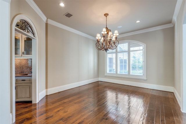 unfurnished dining area with crown molding, dark wood-type flooring, and a chandelier