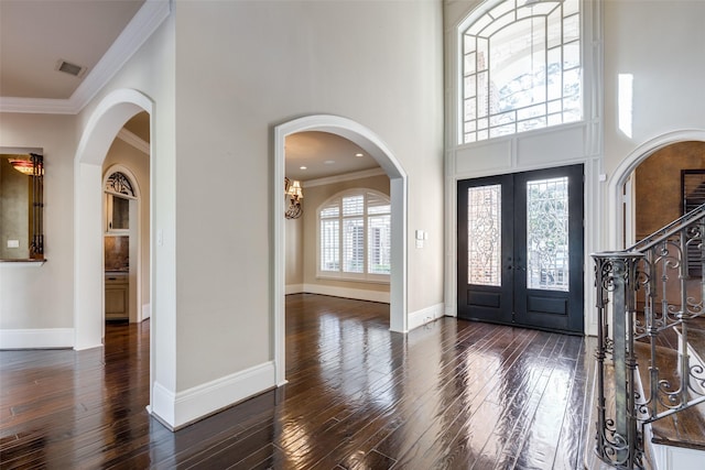 entryway featuring french doors, dark hardwood / wood-style flooring, ornamental molding, and a high ceiling