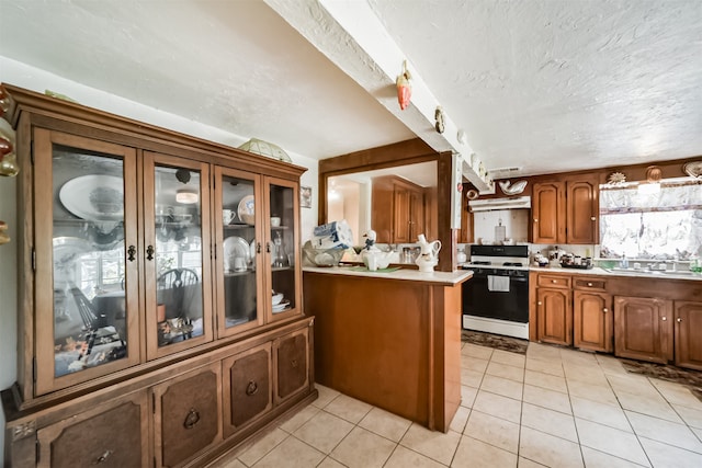 kitchen featuring light tile patterned flooring, a textured ceiling, kitchen peninsula, white gas range oven, and sink