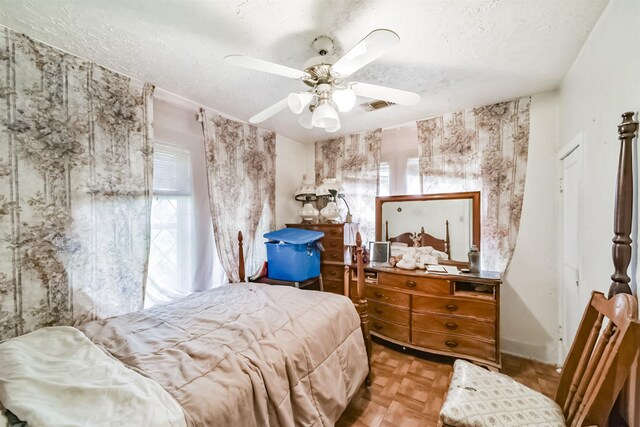 bedroom featuring a textured ceiling, light parquet flooring, and ceiling fan