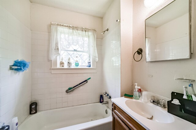 bathroom with tiled shower / bath combo and vanity