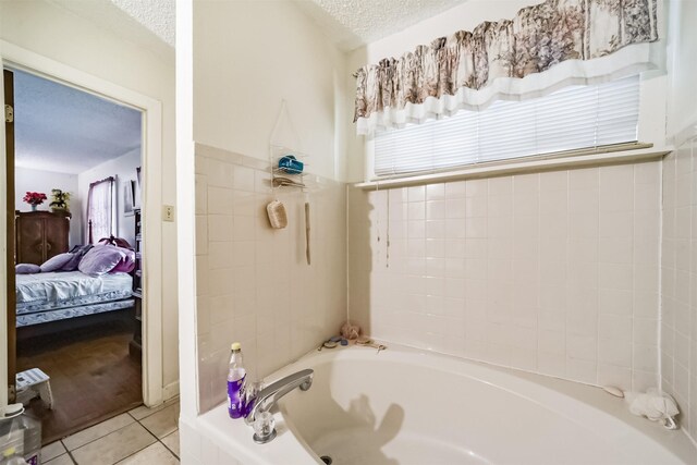 bathroom with tile patterned flooring, a tub to relax in, and a textured ceiling