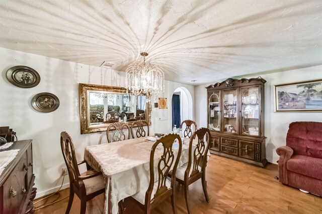 dining space with light hardwood / wood-style floors and a chandelier