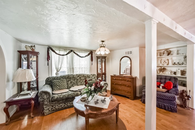 living room with built in shelves, ornate columns, and light hardwood / wood-style floors