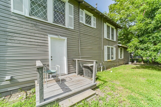 back of house with a wooden deck, a lawn, and cooling unit