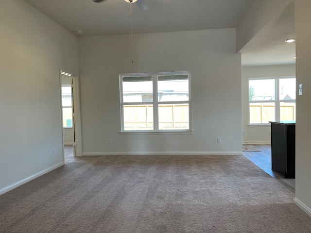 interior space with plenty of natural light, ceiling fan, and light carpet