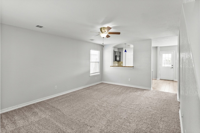 empty room featuring ceiling fan, light carpet, and a wealth of natural light