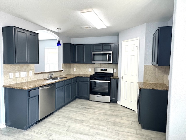 kitchen featuring appliances with stainless steel finishes, light wood-type flooring, pendant lighting, and sink