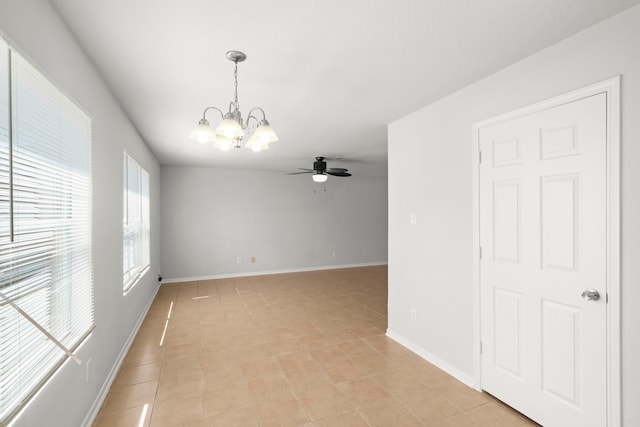 tiled spare room featuring ceiling fan with notable chandelier