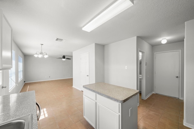 kitchen featuring white cabinetry, decorative light fixtures, ceiling fan with notable chandelier, and light tile patterned floors