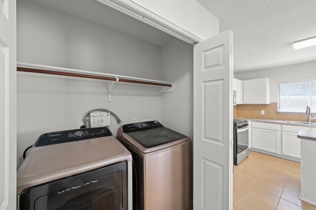 washroom with washer and clothes dryer, sink, and light tile patterned floors