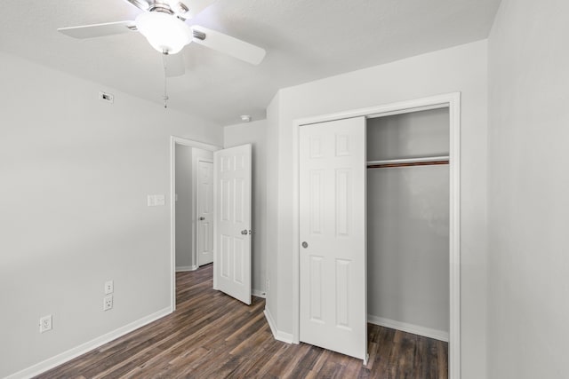 unfurnished bedroom with dark hardwood / wood-style flooring, a closet, and ceiling fan