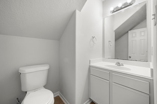 bathroom with vanity, toilet, a textured ceiling, and vaulted ceiling