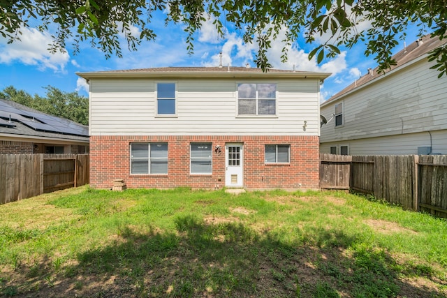 back of property with a lawn and solar panels