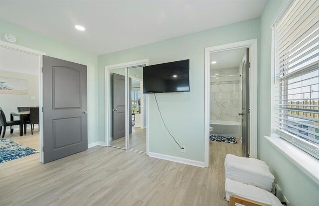 bedroom featuring light wood-type flooring, a closet, and connected bathroom