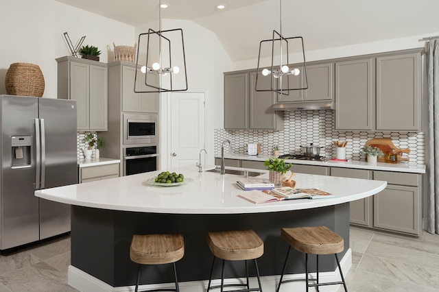 kitchen featuring stainless steel appliances, a chandelier, and a center island with sink