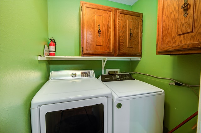 laundry area featuring washing machine and clothes dryer and cabinets