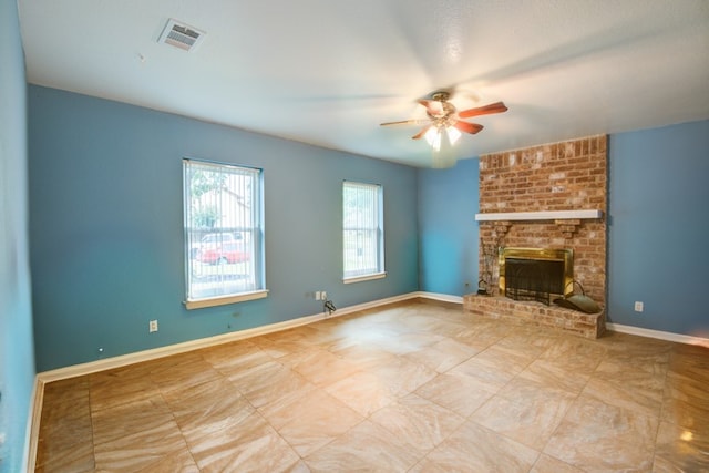 unfurnished living room with a brick fireplace, brick wall, light tile patterned floors, and ceiling fan