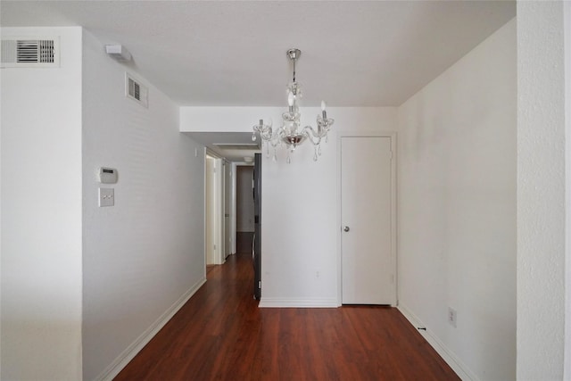 unfurnished dining area featuring dark wood-type flooring and an inviting chandelier