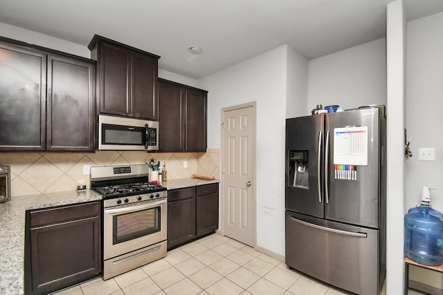 kitchen with appliances with stainless steel finishes, light tile patterned floors, light stone counters, and backsplash