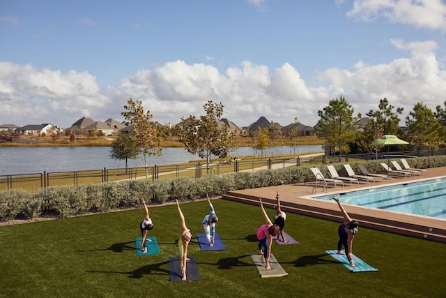 view of property's community with a water view, a swimming pool, and a lawn