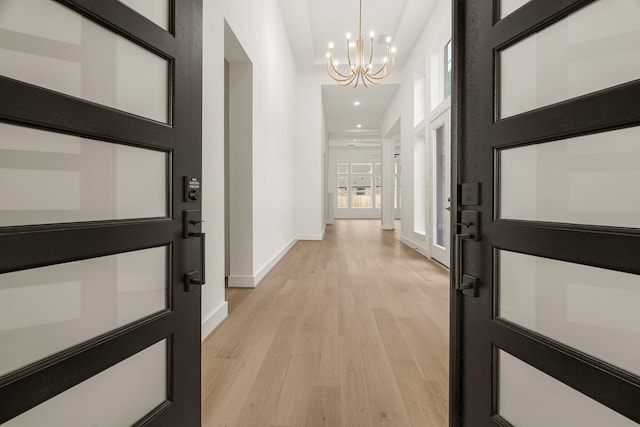 hallway with a notable chandelier and light wood-type flooring