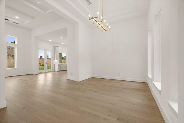 unfurnished room featuring light hardwood / wood-style floors, an inviting chandelier, and french doors