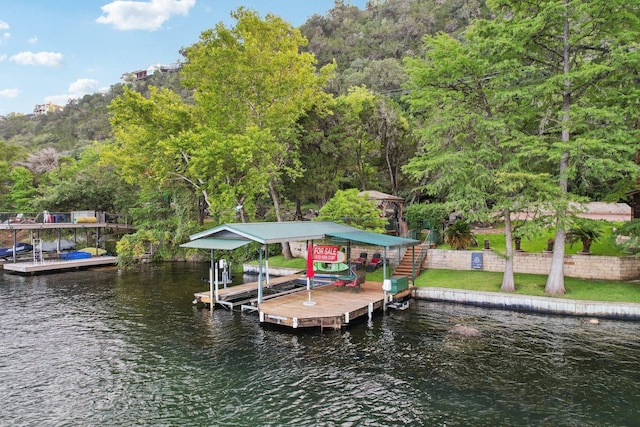 view of dock featuring a forest view, a water view, and boat lift