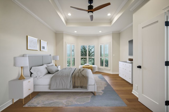 bedroom with dark wood-type flooring, a tray ceiling, ceiling fan, and crown molding