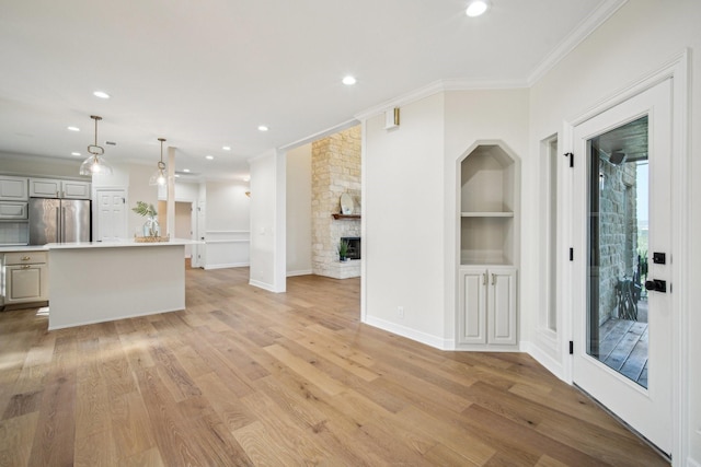 kitchen featuring high end fridge, a fireplace, light wood-style flooring, and crown molding