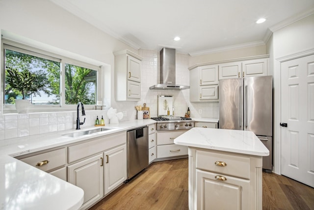 kitchen with ornamental molding, wall chimney exhaust hood, appliances with stainless steel finishes, and a sink