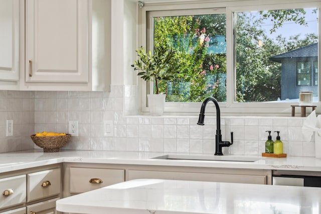 details with white cabinetry, decorative backsplash, sink, and light stone counters