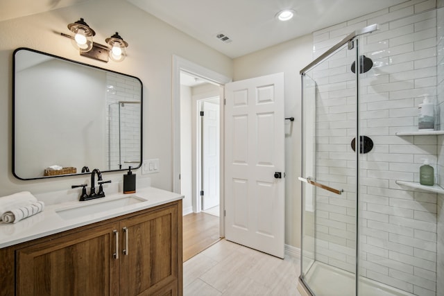 bathroom with an enclosed shower, vanity, and hardwood / wood-style floors