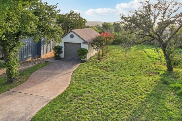 view of front of house with a detached garage, a front lawn, fence, concrete driveway, and an outdoor structure