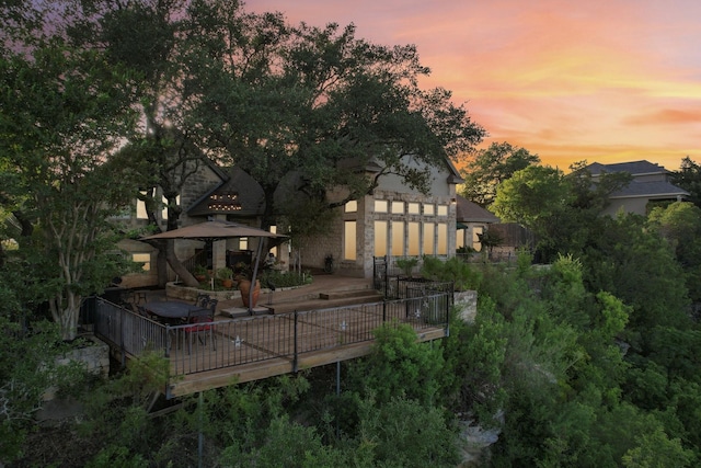 back of house at dusk with a gazebo and a wooden deck