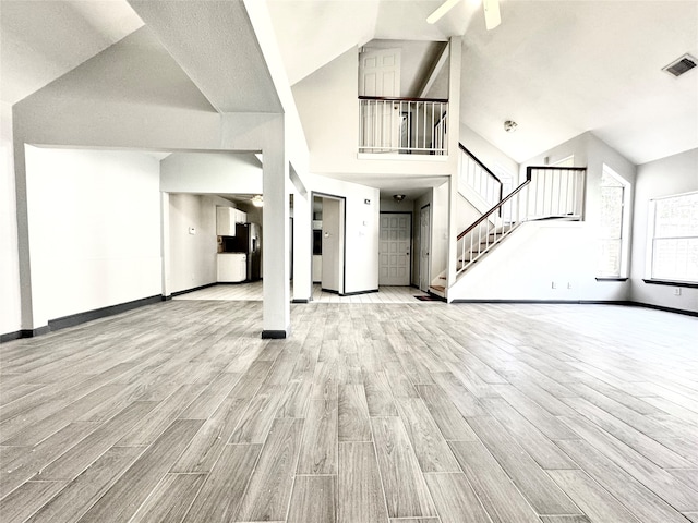 unfurnished living room featuring light hardwood / wood-style flooring, ceiling fan, and a high ceiling