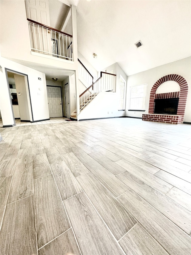 unfurnished living room featuring a high ceiling, a fireplace, and light hardwood / wood-style flooring