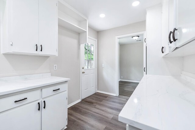 kitchen with white cabinetry, hardwood / wood-style flooring, and light stone counters