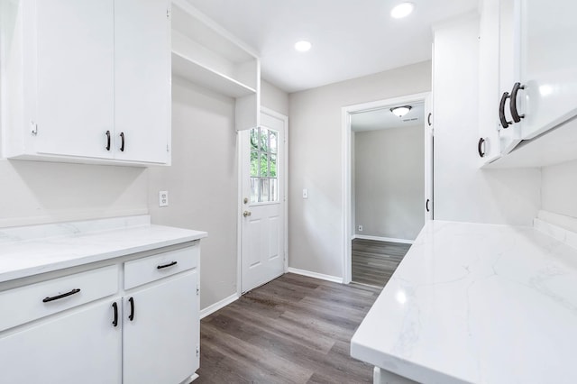 kitchen with hardwood / wood-style flooring, white cabinetry, and light stone countertops