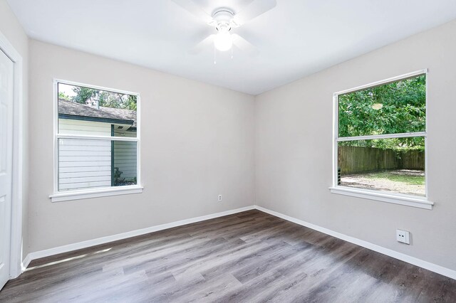 spare room with ceiling fan, wood-type flooring, and plenty of natural light