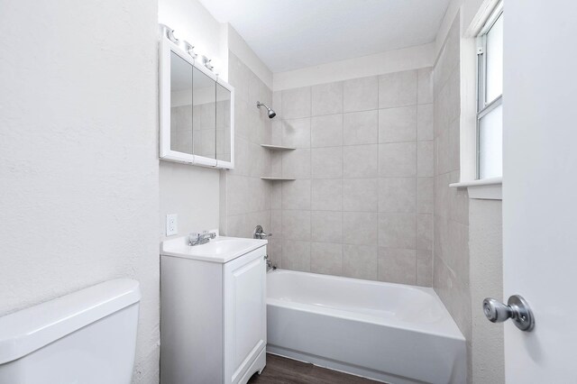 full bathroom with vanity, tiled shower / bath, toilet, and wood-type flooring