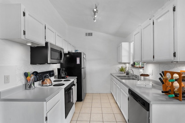 kitchen featuring sink, vaulted ceiling, light tile patterned floors, stainless steel appliances, and white cabinets