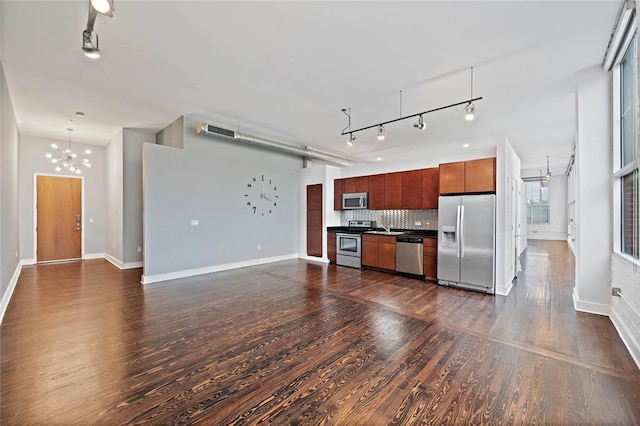 kitchen featuring stainless steel appliances, track lighting, tasteful backsplash, and dark wood-type flooring