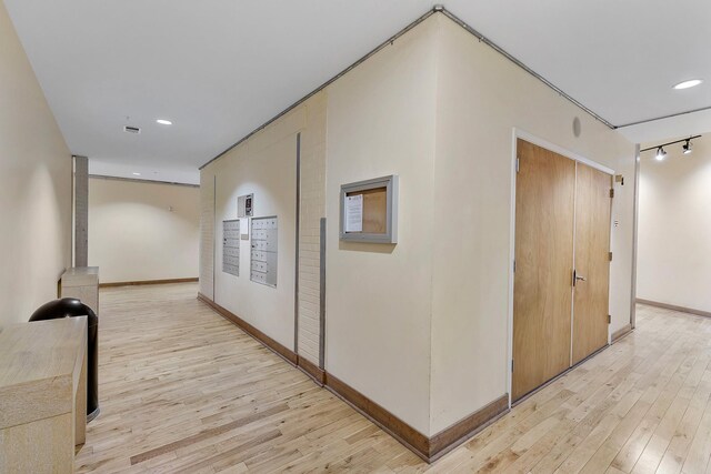 corridor with mail boxes and light hardwood / wood-style flooring