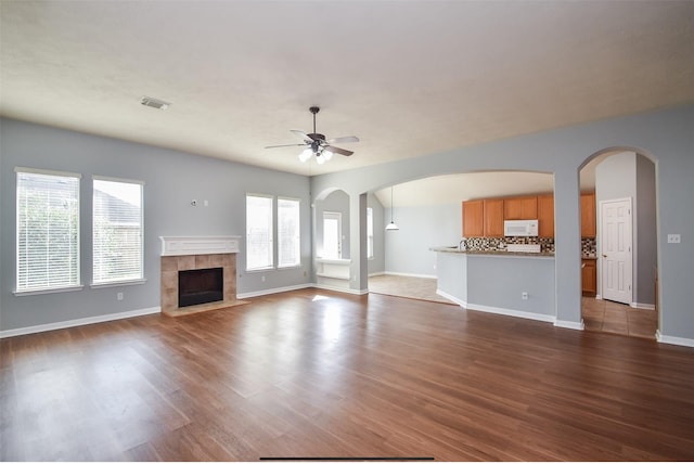 unfurnished living room featuring a fireplace, ceiling fan, and wood-type flooring