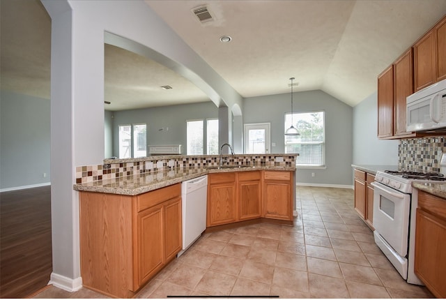 kitchen featuring decorative backsplash, light hardwood / wood-style floors, light stone countertops, sink, and white appliances